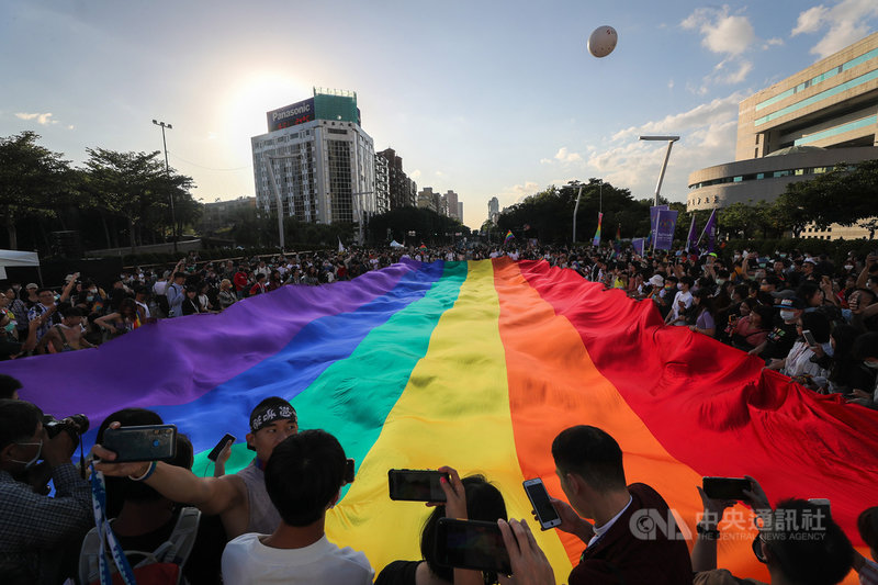 2020第18屆台灣同志遊行31日在台北盛大登場,主辦單位表示,今年有13萬人共襄盛舉,也讓台灣同志遊行成為今年度北半球最大的同志遊行。圖為遊行隊伍抵達終點時,人群圍繞在巨型彩虹旗周邊拍照留念。中央社記者裴禛攝 109年10月31日