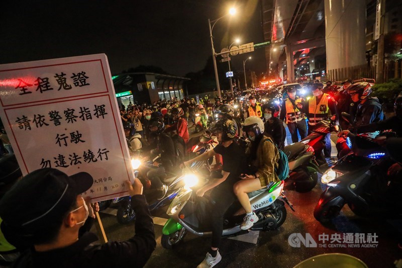 民團為抗議台北市交通局於塔城街與鄭州路口施行強制兩段式左轉,20日晚間號召機車族參與「待轉大富翁」行動,警方派員到路口舉牌警告。中央社記者吳家昇攝 109年11月20日
