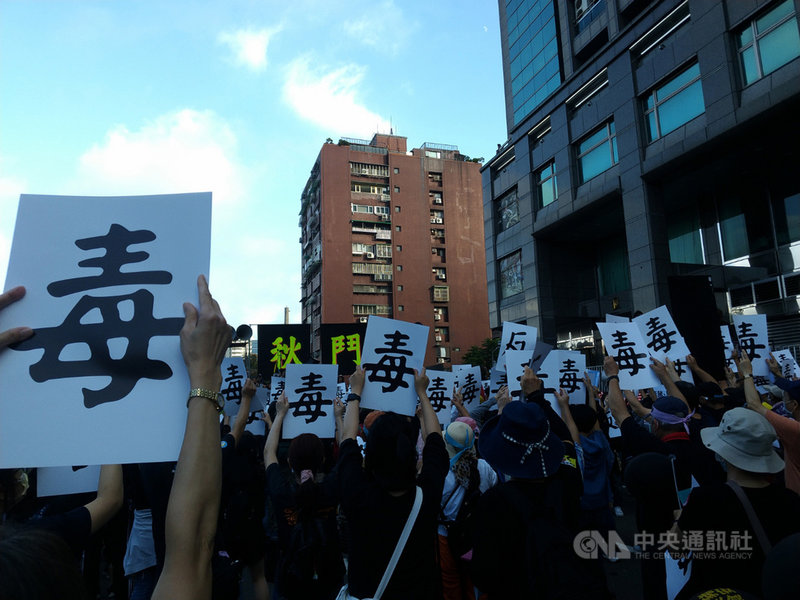 秋鬥遊行22日下午登場,遊行隊伍抵達民進黨中央黨部,民眾高舉正反面分別印有「毒」、「反」的字牌,並高喊口號,表達反萊豬訴求。中央社記者張雄風攝 109年11月22日