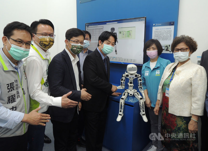 副總統賴清德(前左4)24日到台中精密機械園區參訪智慧製造技術驗證場域,分別參觀口罩鋼輪、無人搬運車、鞋子模具、機器人等設施,與機器人互動握手。中央社記者郝雪卿攝 109年11月24日