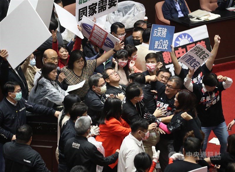 行政院長蘇貞昌27日第13度赴立法院進行施政報告並備質詢,民進黨立委27日護衛蘇貞昌(拿麥克風者)上台,報告時有國民黨立委向主席台倒動物內臟,雙方在台前爆發衝突。中央社記者張新偉攝 109年11月27日