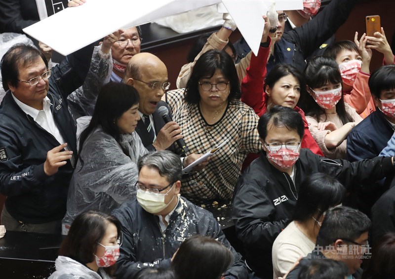 行政院長蘇貞昌27日第13度赴立法院進行施政報告,民進黨立委27日護衛蘇貞昌(拿麥克風者)上台報告,報告時有國民黨立委向主席台倒動物內臟,阻擋施政報告,民進黨以人牆及看板護衛遮擋。中央社記者張新偉攝 109年11月27日