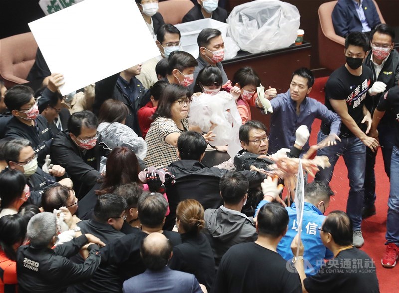 行政院長蘇貞昌27日第13度赴立法院進行施政報告並備質詢,民進黨立委27日護衛蘇貞昌上台報告,報告時有國民黨立委向主席台倒動物內臟,民進黨立委王美惠(中)將內臟丟回給國民黨立委。中央社記者張新偉攝 109年11月27日
