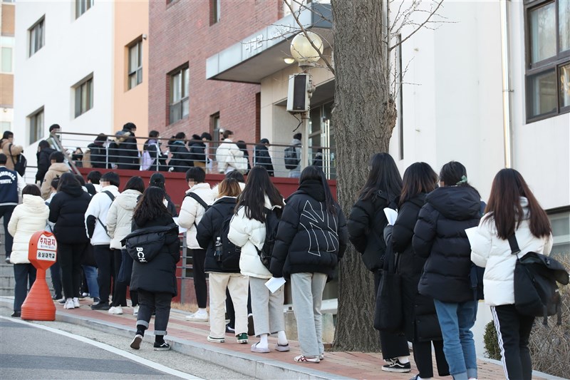 韓國專家指出,剛結束大學聯考的高3考生「出關」,將成疫情變數。圖為韓國考生排隊量體溫、進考場。(韓聯社)