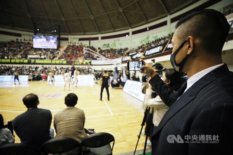台灣職業籃球聯盟P. LEAGUE+ 開幕戰19日在彰化縣立體育館開打,聯盟執行長陳建州(右)在場邊觀看比賽,不時拿起手機記錄現場。中央社記者張新偉攝 109年12月19日