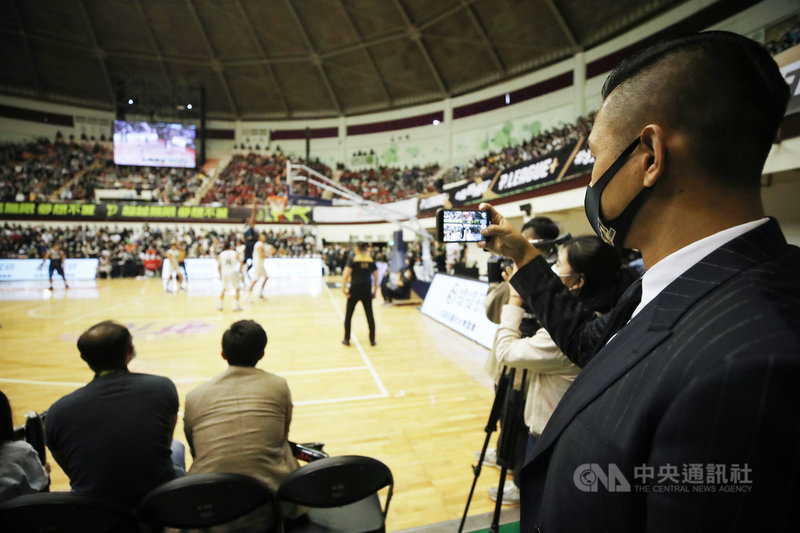 台灣職業籃球聯盟P. LEAGUE+ 開幕戰19日在彰化縣立體育館開打,聯盟執行長陳建州(右)在場邊觀看比賽,不時拿起手機記錄現場。中央社記者張新偉攝 109年12月19日