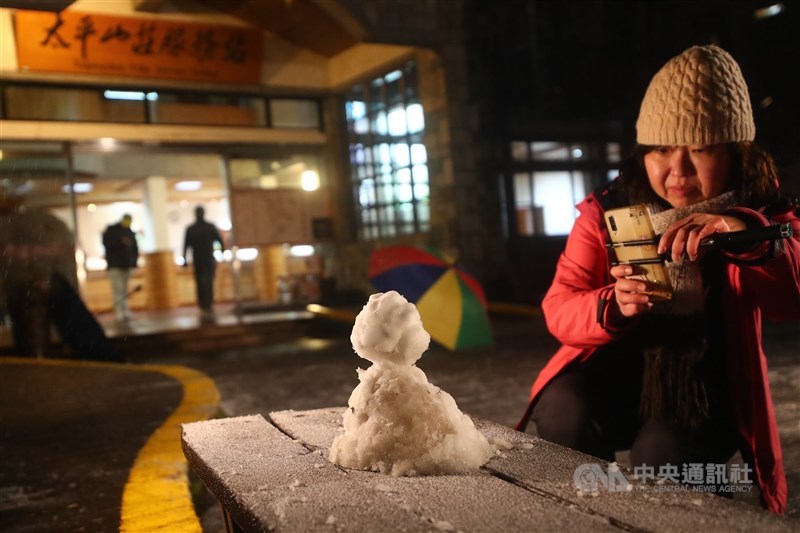 寒流襲台,太平山國家森林遊樂區7日晚間開始下雪,太平山莊前有遊客堆起小雪人,吸引眾人拍照留念。中央社記者王騰毅攝 110年1月7日