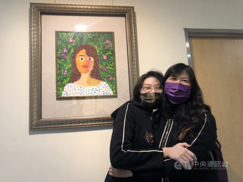 罹患罕見疾病的于昕蕎(左)在童綜合醫院舉辦畫展,8日在畫作前與母親相擁,以畫作傳遞對母親滿滿的愛。中央社記者趙麗妍攝 110年1月8日