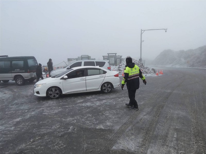 合歡山因寒流來襲下雪,路面結冰,台14甲線29公里處,也就是昆陽停車場往鳶峰方向,大轉彎處路面結冰比較厚,即使小型車加掛雪鍊也很難開到昆陽停車場。圖為南投警方指揮上山車輛情形。(翻攝照片)中央社記者吳哲豪傳真 110年1月9日