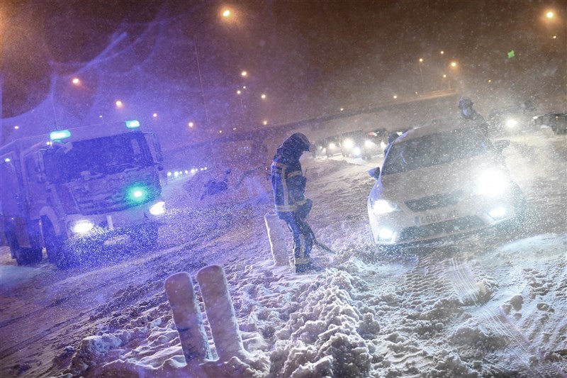 西班牙遭遇半世紀以來最大降雪，導致至少3人喪命，全國多數地區陷入混亂，數以千計的駕駛受困路中。圖為8日馬德里消防員幫助受困駕駛。（法新社）