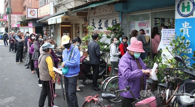 政府為防疫接連宣布禁止醫用口罩輸出、徵用廠商生產的口罩、成立口罩國家隊、口罩以實名制販售等措施。圖為去年3月間民眾排隊購買口罩。(中央社檔案照片)