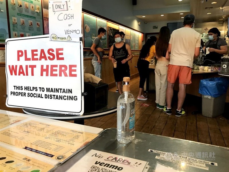 美國疾病管制暨預防中心24日表示,正加強追蹤新型冠狀病毒突變情形。圖為洛杉磯飲料店管制人流並設置消毒液。(中央社檔案照片)
