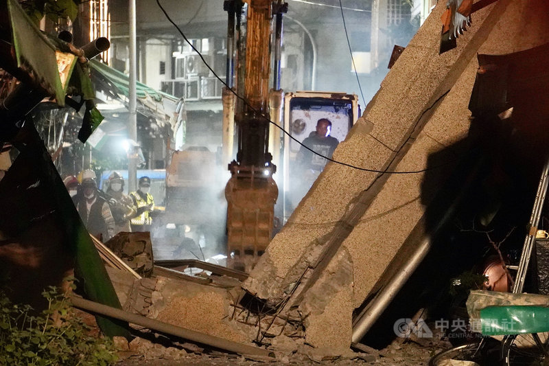 在高雄市新興區八德二路、同愛街口,前身為舊今日戲院的老舊建物28日下午發生外牆倒塌意外,晚間消防局和工務局進駐,出動大型機具將清除路面坍塌部分。中央社記者董俊志攝 110年1月28日
