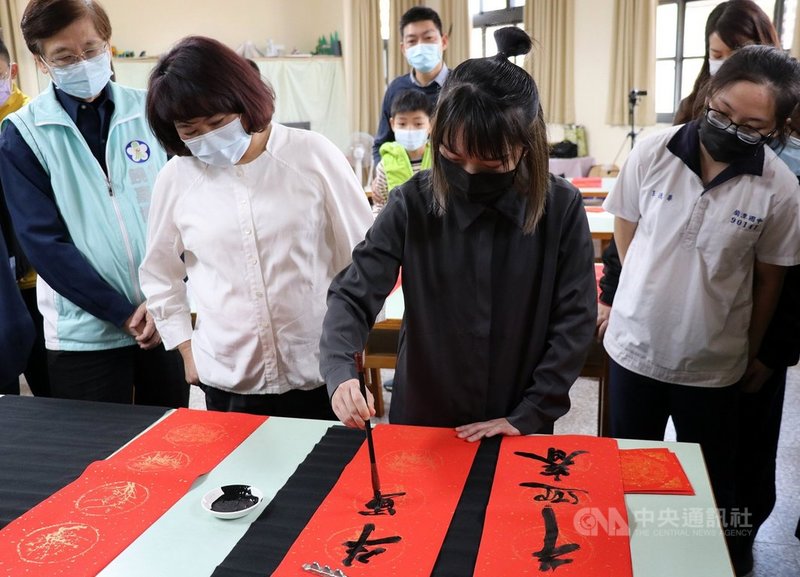 總統府今年春聯「牛轉乾坤」由嘉義年輕女書法家王意淳（前右2）執筆，她29日回母校嘉義市蘭潭國中分享學習歷程，並現場揮毫寫春聯。前左2為嘉義市長黃敏惠。中央社記者黃國芳攝  110年1月29日