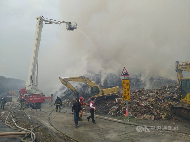八里垃圾掩埋場廢棄物持續悶燒,新北警消已加派消防人車搭配挖土機等重機械進行殘火處理。(翻攝照片)中央社記者王鴻國傳真 110年3月1日