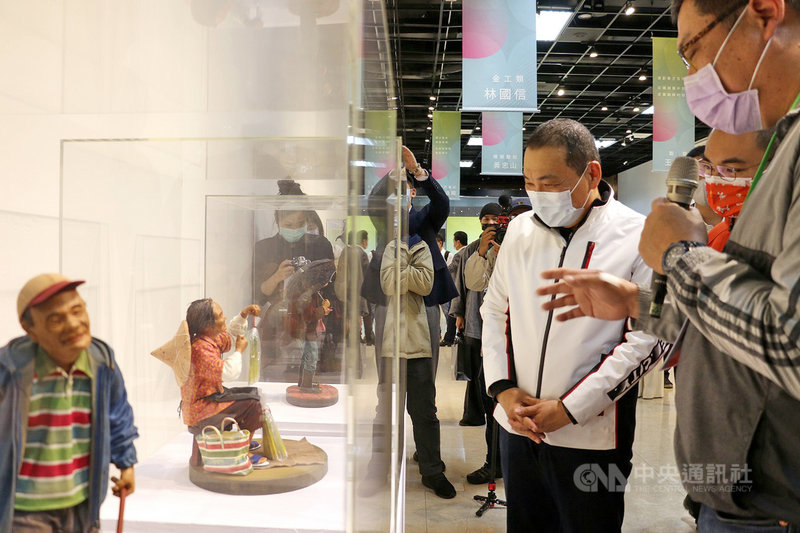 「工藝之華-新北市台灣工藝之家」聯展6日下午開幕,市長侯友宜(白衣者)出席參觀,工藝師段安國(右)親自為侯友宜解說自己創作的皮革作品。(新北市文化局提供)中央社記者黃旭昇新北市傳真 110年3月6日