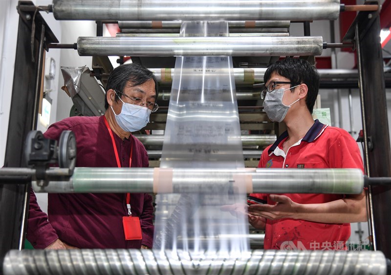 銘安科技董事長黃建銘(左)檢視著剛成形的生物可分解塑膠膜,準備逐步擴大產能,搶攻綠金市場。中央社記者鄭清元攝 110年3月7日