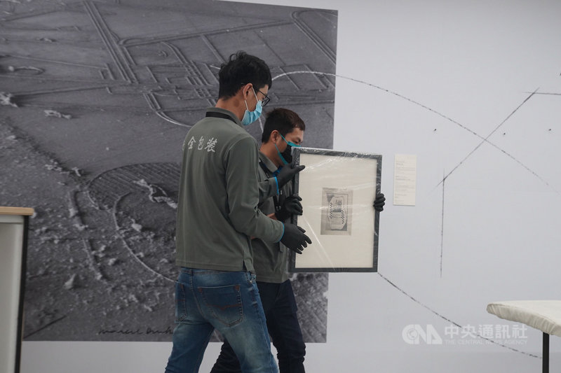 國家攝影文化中心台北館8日舉行首檔國際展「塵與時:從宇宙到居所」開箱記者會,工作人員搬出曼.雷(Man Ray)的作品。中央社記者徐肇昌攝 110年3月8日