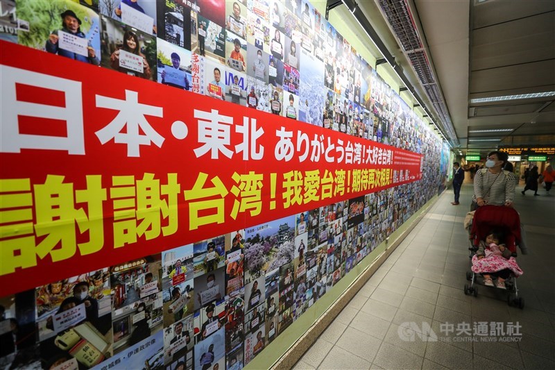 在台灣經營旅遊顧問公司的日籍男子向井純自掏腰包,徵集1200多名日本東北地區的民眾,以照片和寫給台灣的話,做成「謝謝台灣!我愛台灣!」的大型海報,刊登在台北捷運中山站。 中央社記者裴禛攝 110年3月10日