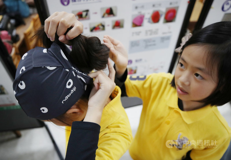 台灣學子參加2020世界青少年發明展共拿下28面金牌,12日獲教育部表揚,其中嘉義大學附小學生楊喆媗(左)、黃靖琁(右)設計出一款長髮、短髮者都能配戴的泳帽,利用雙層布料,長髮者可把馬尾從「髮洞」抓出,再收到內外層彈力布空間中,完整包覆頭髮不外露。中央社記者張新偉攝 110年3月12日