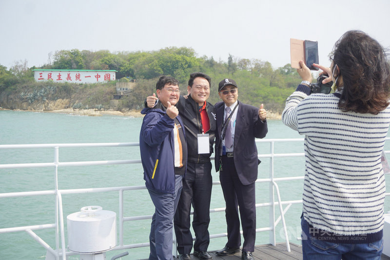 金廈遊輪「初日號」13日在金門水頭碼頭首航,行經大膽島海域時,民眾紛紛登上甲板觀看著名心戰牆「三民主義統一中國」並開心留影。中央社記者黃慧敏攝 110年3月13日