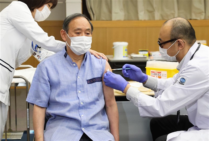 日本首相菅義偉(中)16日完成施打第1劑COVID-19疫苗。(共同社)