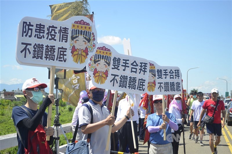 去年6月14日台中大甲鎮瀾宮媽祖遶境抵達嘉義縣新港鄉,新港奉天宮派人在崙子橋上舉牌,呼籲民眾不鑽轎底。(中央社檔案照片)