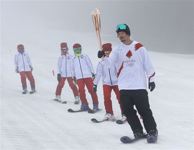 日本東京奧運聖火傳遞25日正式從福島縣起跑,26日滑雪選手遠藤尚(前)與豬苗代町當地孩童組隊傳遞聖火。(共同社)