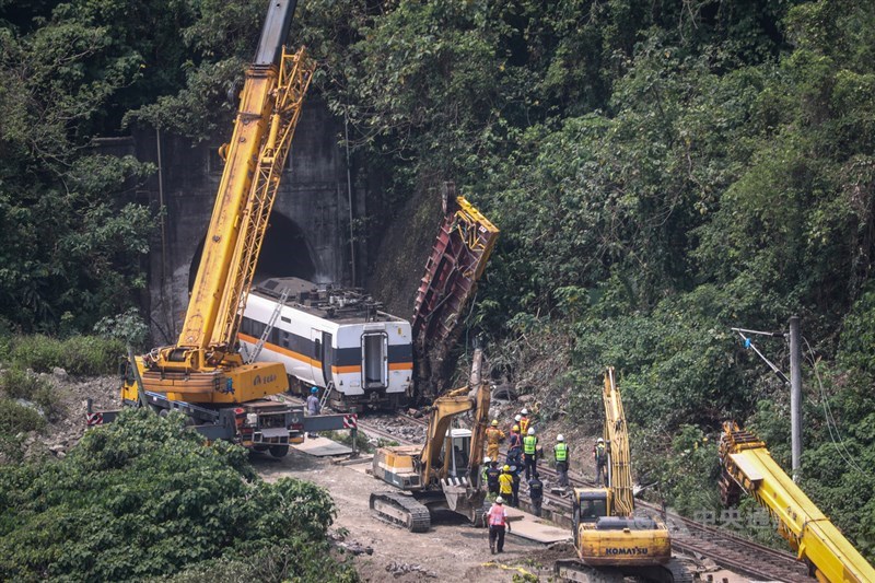 台鐵408車次太魯閣號2日在花蓮清水隧道疑遭工程車砸中出軌,造成50人死亡。台鐵3日上午進行搶修工作,陸續將車廂吊掛拉出,並將工程車吊離邊坡。中央社記者吳家昇攝 110年4月3日
