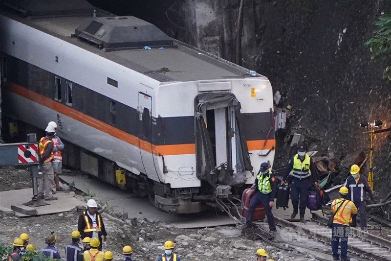 台鐵太魯閣號出軌事故造成重大傷亡,4日事故現場持續進行搶通,員警們從車廂內攜出旅客行李行經第4節車廂。中央社記者徐肇昌攝 110年4月4日