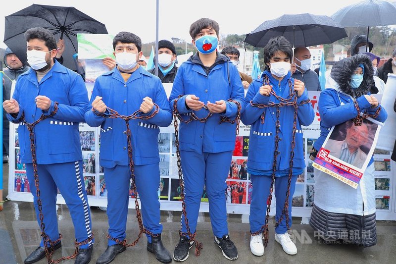 維吾爾人5日赴中國駐伊斯坦堡總領事館外示威,身穿藍色制服的5名男女手腳遭到鐵鍊束縛,藉以象徵維吾爾人所受苦難。中央社記者何宏儒伊斯坦堡攝 110年4月5日