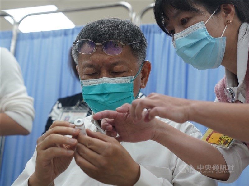 台北市長柯文哲(左)12日在台北市立聯合醫院和平院區接種AZ疫苗,護理人員在施打前向柯文哲說明疫苗內容與保存期限。中央社記者徐肇昌攝 110年4月12日