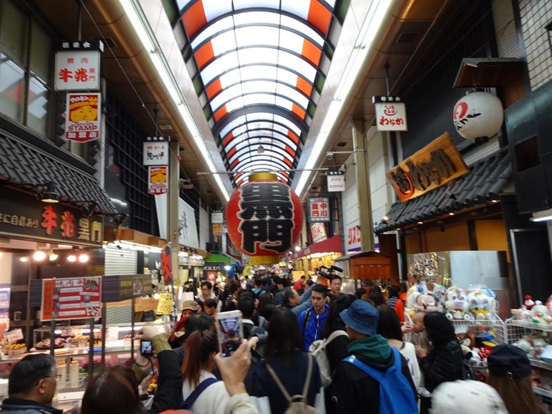 日本大阪黑門市場近日因疫情少了外國客,日本人也不愛去,生意慘淡。圖為黑門市場昔日人潮洶湧情況。(中央社檔案照片)