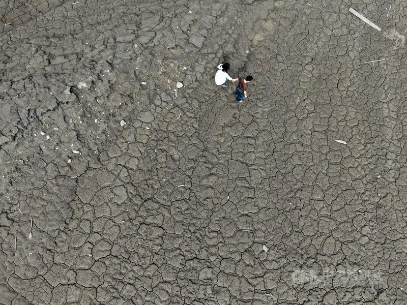水情吃緊,桃園石門水庫蓄水率已不到3成,上游集水區大範圍乾涸見底,17日遊客到訪水庫,踏在龜裂的裸露土表上。中央社記者王騰毅攝 110年4月17日