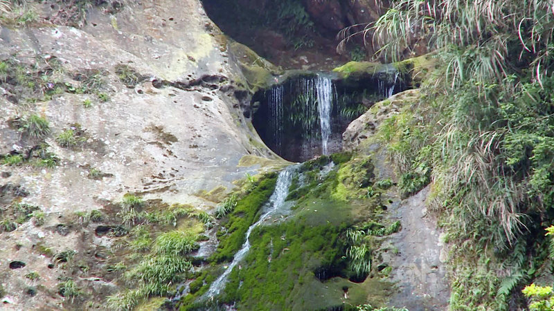 杉林溪森林生態渡假園區的松瀧岩瀑布近來因旱象變成涓涓流水,遊客戲稱水量彷彿水龍頭。園區18日表示,枯水期水量會較小,但今年「巨瀑變涓流」的確是開園以來少見。(翻攝畫面)中央社記者蕭博陽南投縣傳真 110年4月18日