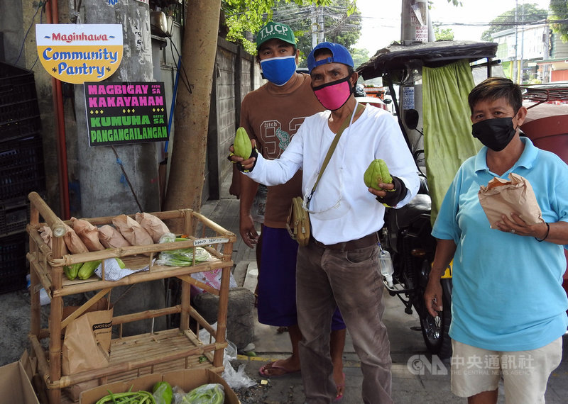 菲律宾女创业家诺恩在大马尼拉地区奎松市街边立起竹制小矮柜，供贫困民众领取食物，命名为「麦金哈瓦社区食橱」，在全菲掀起社区食物银行风潮。图为当地民众4月18日与社区食橱合影。中央社记者陈妍君马尼拉摄　110年5月2日