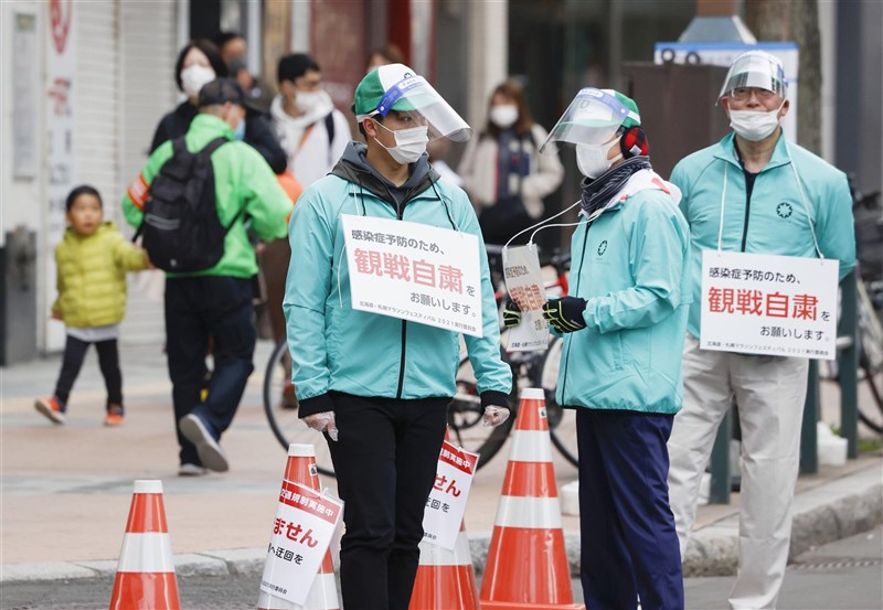 日本政府正研擬延長實施緊急事態,考量將北海道等處納入防止蔓延等重點措施。圖為5日北海道舉行東京奧運馬拉松測試賽,工作人員以告示提醒觀眾賽事不開放參觀。(共同社)