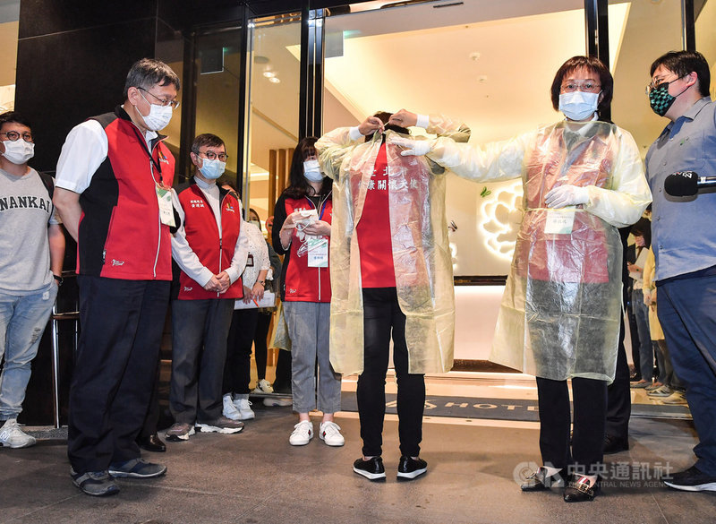 台北市長柯文哲(前左)6日晚間視察台北市防疫旅館,觀看旅館防疫人員示範穿上隔離衣。中央社記者鄭清元攝 110年5月6日
