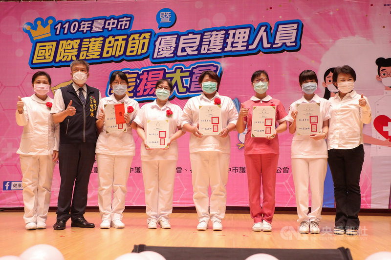 台中市政府7日在市府集會堂舉辦「110年台中市國際護師節暨優良護理人員表揚大會」,市長盧秀燕(右)代表向台中市2萬多名執業護理人員致敬。中央社記者郝雪卿攝 110年5月7日
