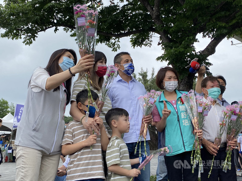 母親節前夕,民進黨台北市黨部主委吳怡農(前右3)8 日與同黨市議員簡舒培(前右2)、鍾佩玲(左)等人一同分送康乃馨給民眾,祝福媽媽們母親節快樂。中央社記者黃麗芸攝 110年5月8日