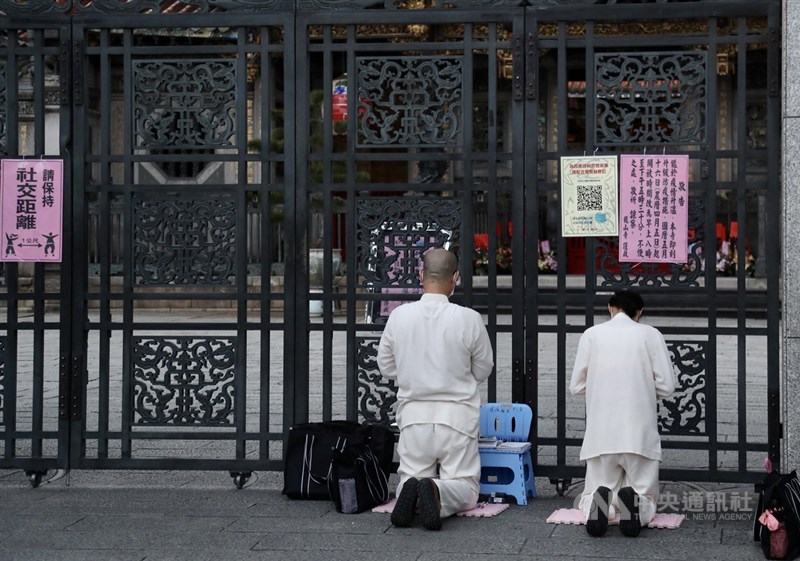 萬華龍山寺關起廟門，暫時不開放信眾入內，有民眾16日在龍山寺大門跪地參拜。中央社記者張皓安攝 110年5月16日