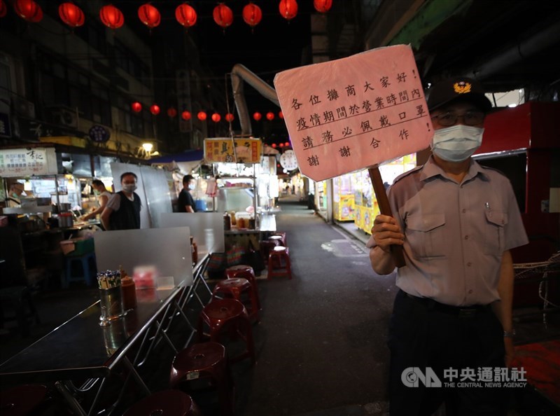 疫情升溫,雙北進入3級防疫警戒,饒河街觀光夜市15日人潮零星,工作人員持續高舉告示牌,提醒民眾戴好口罩防疫。中央社記者張新偉攝 110年5月15日