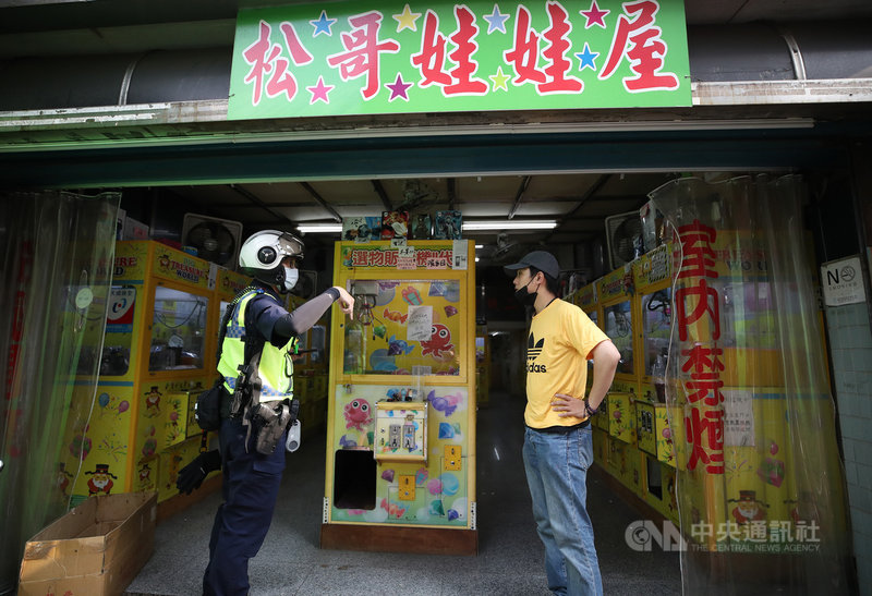 台北市17日召開疫情記者會宣布,娃娃機店與釣蝦場、桌遊店、附設卡啦OK的餐飲業關閉,避免人潮聚集。台北市員警巡視轄區內娃娃機店是否如期停業並進行宣導。中央社記者張新偉攝 110年5月17日
