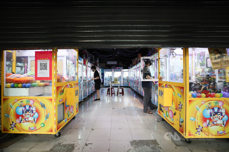 台北市17日召開疫情記者會宣布,娃娃機店與釣蝦場、桌遊店、附設卡啦OK的餐飲業關閉。娃娃機店場主拉下鐵門停業,同時為店裡機台消毒。中央社記者張新偉攝 110年5月17日