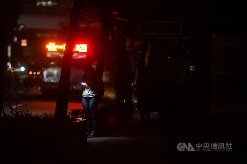 17日晚間8時左右國家警報大響,台電表示,晚間8時10 分因負載突升,供電能力不足,8時50分執行分區輪流停電。圖為台北市民權東路六段停電,民眾在公車站摸黑等車。中央社記者裴禛攝 110年5月17日
