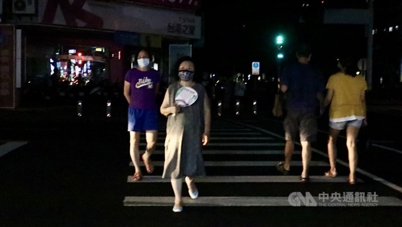台電表示,17日晚間7時30分負載仍達3487.2萬瓩。興達電廠1號機雖已併聯並緩步升載,但發電量提升需要時間;晚間8時10分因負載突升,供電能力不足,8時50分執行分區輪流停電。圖為高雄市前鎮區一心路上一片漆黑,民眾耐不住悶熱天氣,到戶外降溫。中央社記者董俊志攝 110年5月17日