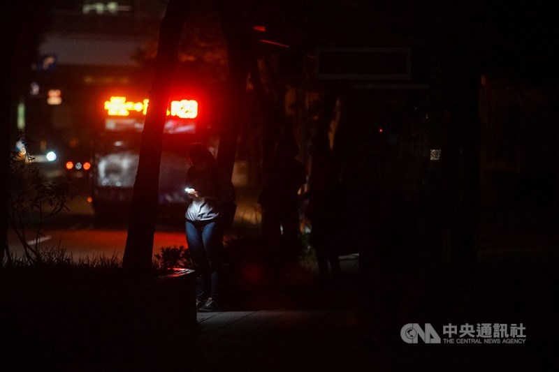 17日晚間8時左右國家警報大響,台電表示,晚間8時10分因負載突升,供電能力不足,8時50分執行分區輪流停電。圖為台北市民權東路六段停電,民眾在公車站摸黑等車。中央社記者裴禛攝 110年5月17日