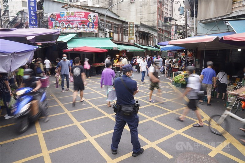 全台防疫三級警戒，北投市場和其他傳統市場一樣正常營運，前來採買的民眾都戴好口罩；員警站在市場動線上維持秩序。中央社記者徐肇昌攝　110年5月22日