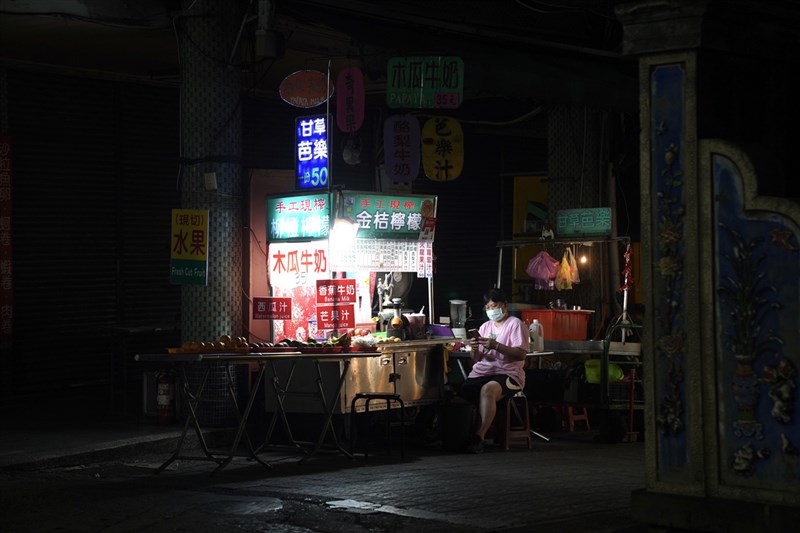 週末夜間開店不見客人上門，飲料攤老闆得閒滑手機。中央社記者徐肇昌攝 110年5月22日