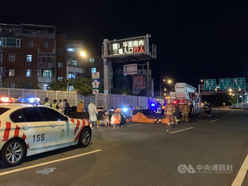 國道1號三重交流道26日晚間有長髮女子攀上匝道電子號誌牌上,警消獲報後穿著全套防護裝備到場,將人救下送醫。中央社記者王鴻國攝 110年5月26日
